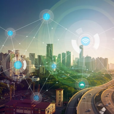 A city skyline of skyscrapers and tower blocks, with a busy road in the foreground