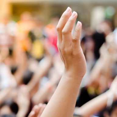 A hand raised in the air, with a blurred crowd in the background